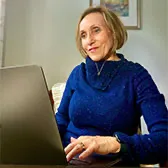 Kasia in a navy blue sweater sitting in front of a computer while working on it